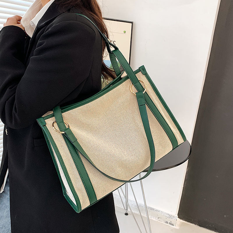 Person holding a EMILY beige canvas handbag with green straps 