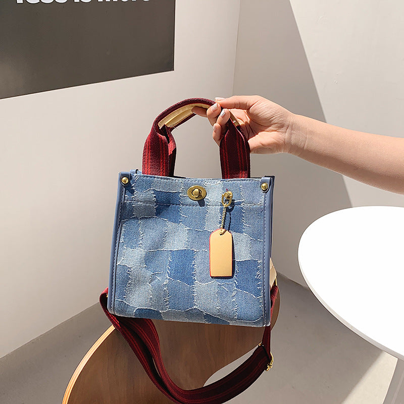 Person holding middle size AMANDA blue denim style patterned handbag with red straps