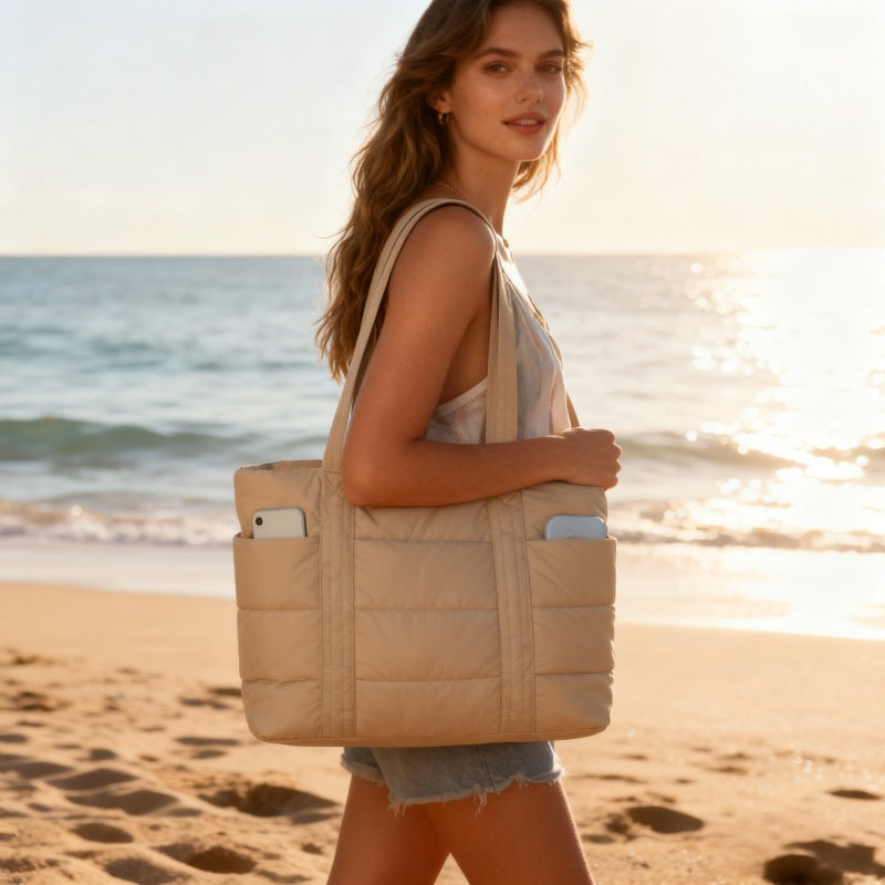 Woman holding a beige DAISY lunch tote bag on a beach at sunset