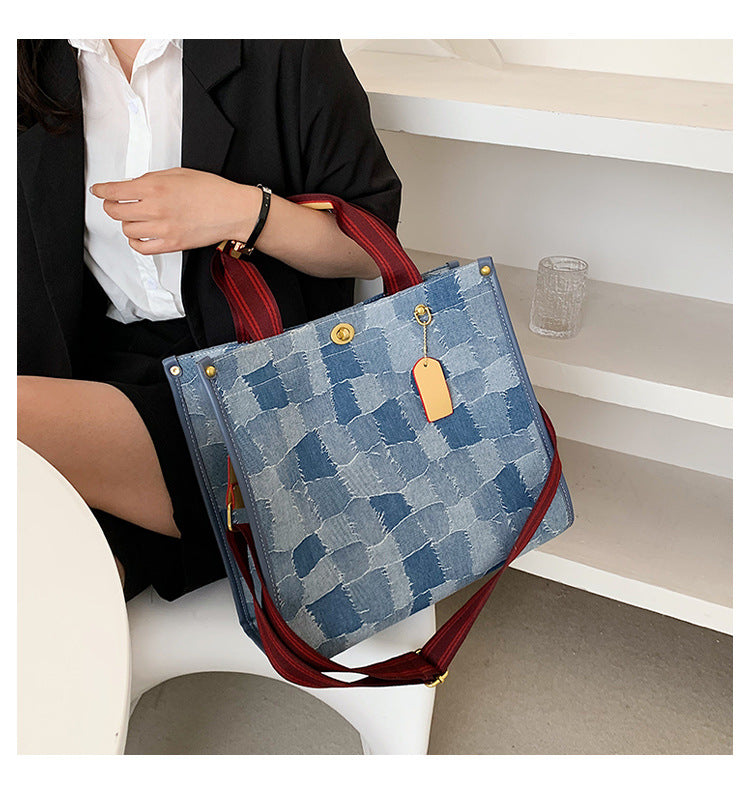 Person holding middle size AMANDA blue denim style patterned handbag with red straps